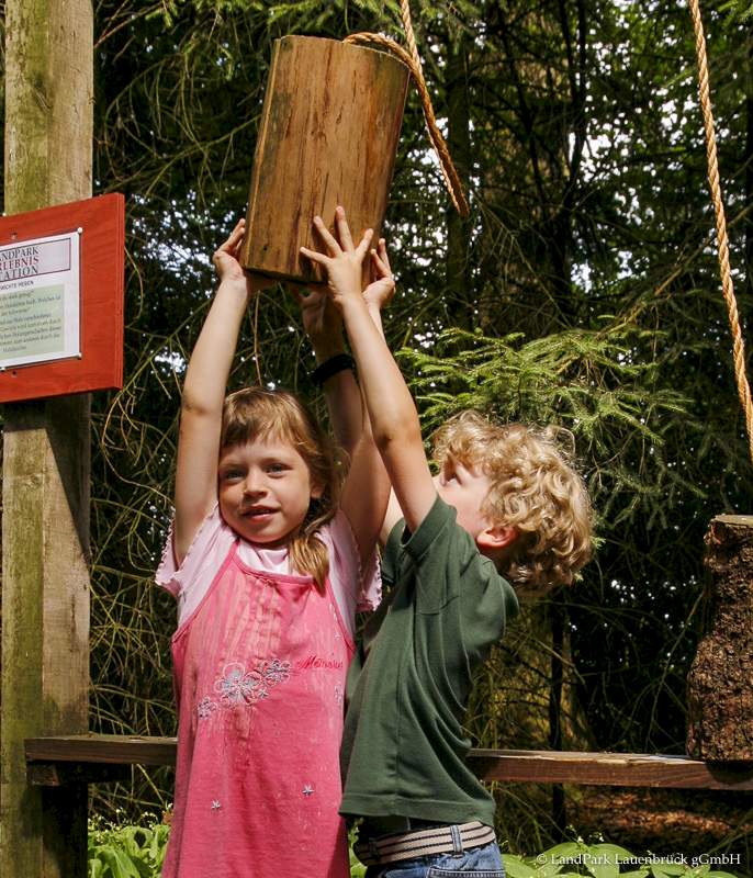 2 Kinder stemmen einen Baumgewicht in die Höhe